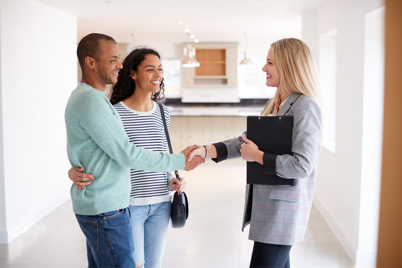 Female realtor shaking hands with the male half of a young couple