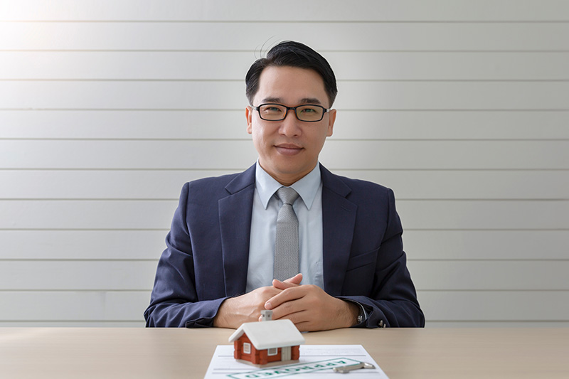 Loan officer sitting at table facing viewer, smiling, with mortgage-related items on the table