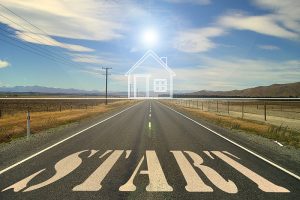 Photo for article on planning home buying journey looking down a long straight country highway with a white line drawing of a house on the horizon